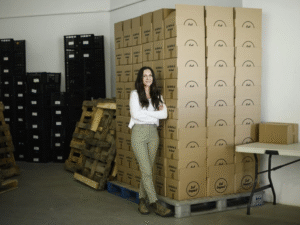 photo of Anna Stegink standing near Eat Impact boxes.